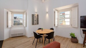 Een moderne woonkamer met een eettafel, zwarte stoelen, een rode bank en een televisie.