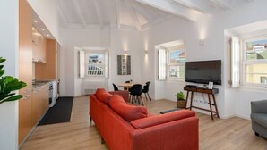 Een moderne woonkamer met een bank, een televisie en een eethoek met stoelen.