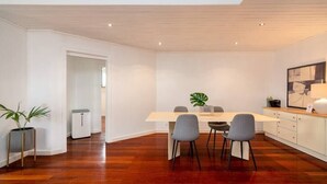 Ein moderner Essbereich mit einem Holztisch, vier grauen Stühlen und einem Blumentopf.