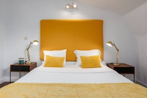 A hotel room with a large bed, two bedside tables, and a wall-mounted light fixture.
