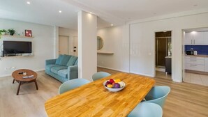 Een moderne woonkamer met een houten eettafel, lichtblauwe stoelen, een bank en een televisie.