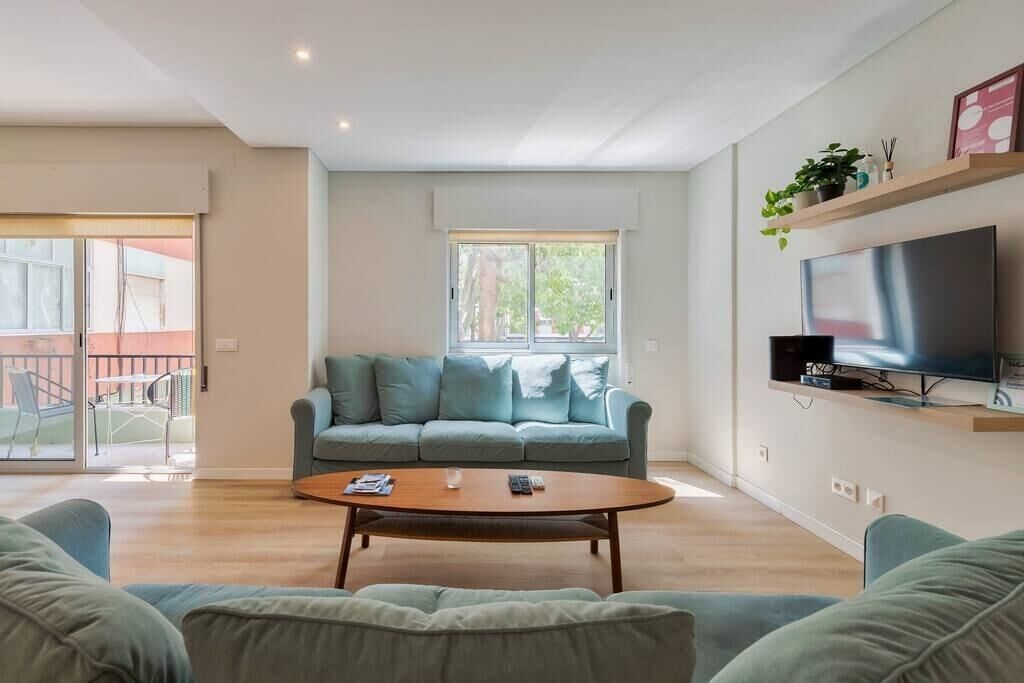 Una sala de estar moderna con un sofá, una mesa de centro y un televisor montado en la pared.