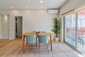 Een moderne eetruimte met een houten tafel, teal stoelen en een potplant.