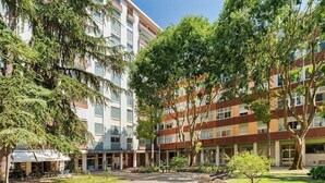 Een binnentuin met een centraal zitgedeelte, omringd door meer verdiepingen tellende gebouwen met balkons.
