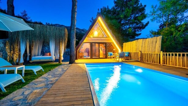 Un chalet confortable doté d’une piscine, d’une terrasse en bois et d’un espace salon extérieur.