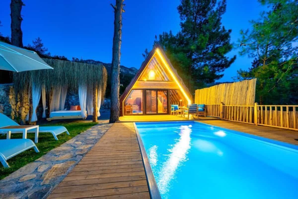 A cozy cabin with a swimming pool, wooden deck, and outdoor seating area.