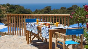 A wooden table set with a blue and white tablecloth, surrounded by blue chairs, with a view of the sea in the background. - Faralya Tuz Hotel (Fethiye)