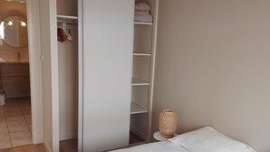 A bedroom with a bed, a wardrobe, and a bedside table with a lamp.