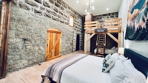 Een gezellige slaapkamer met een stenen muur, een houten trap en een stapelbed.