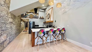 Een moderne keuken met een centraal eiland, houten stoelen en hanglampen.