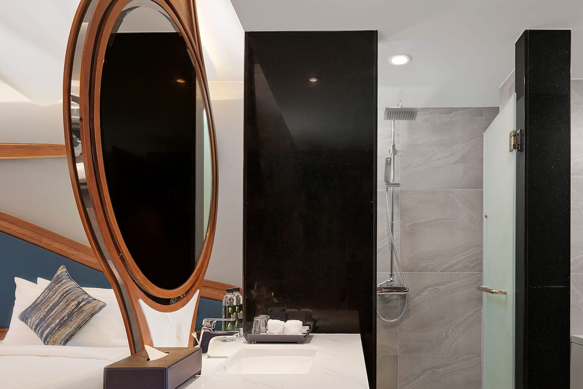 A modern bathroom with a large mirror, a shower, and a vanity with toiletries.