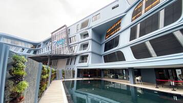 A modern building with a pool, featuring a unique architectural design with multiple levels and balconies.