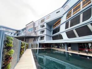 Un hotel moderno con piscina, varios pisos y un diseño arquitectónico único.