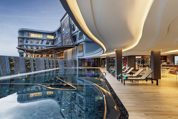 A modern hotel interior with a pool, lounge area, and a distinctive curved ceiling. - The Oceanic Sportel (Ko Kaeo)