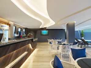 A modern bar area with a counter, seating, and a television screen. - The Oceanic Sportel (Ko Kaeo)