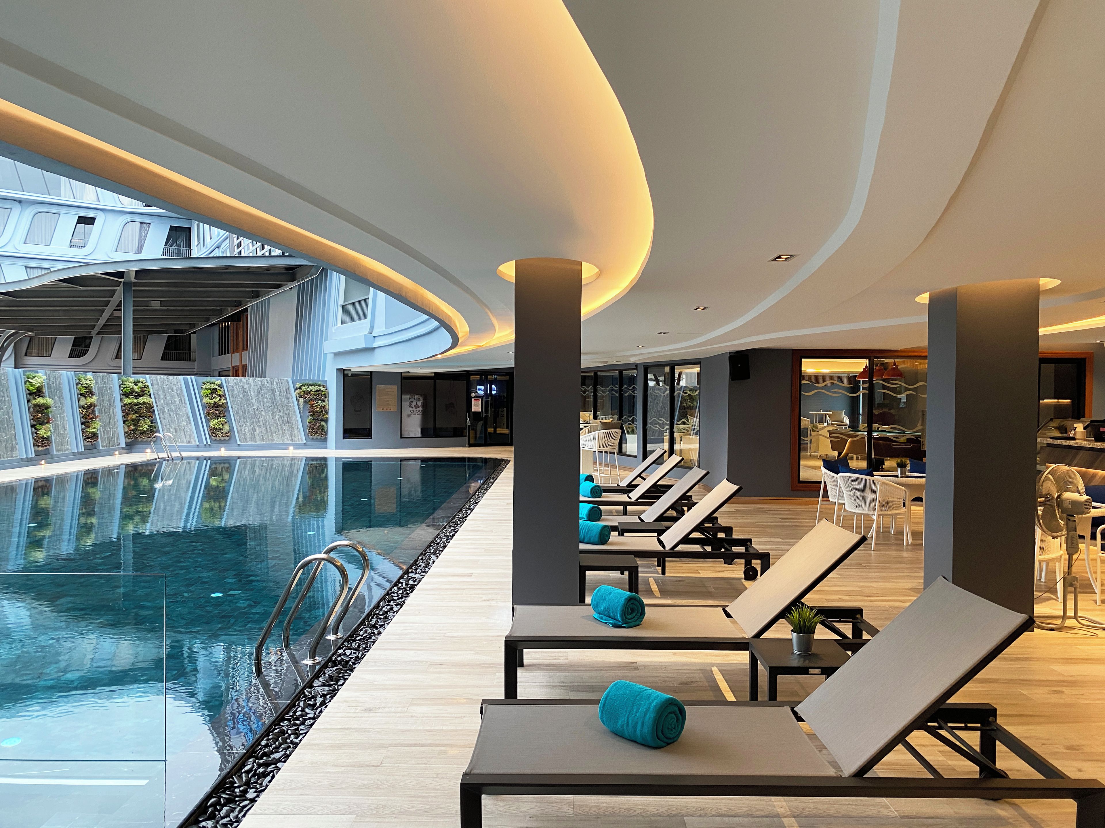 A modern indoor pool area with lounge chairs and a waterfall feature.