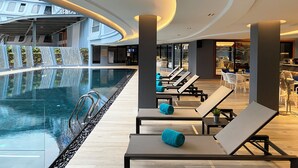Un área de piscina interior moderna con sillones de descanso y una cascada.