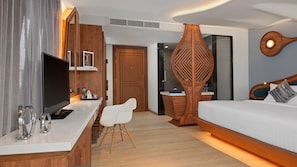 A modern hotel room with a wooden desk, a bed, and a decorative wall piece. - The Oceanic Sportel (Ko Kaeo)