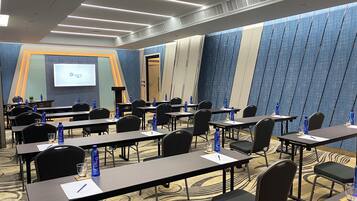 A conference room with tables, chairs, and a presentation screen.