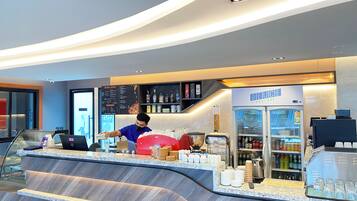 A modern bar area with a counter, a beverage dispenser, and a refrigerated display.