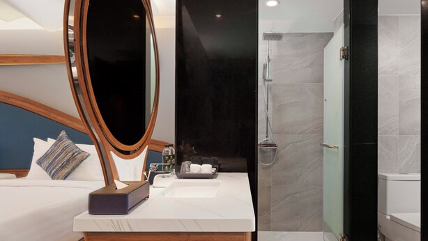 Un baño moderno con un espejo grande, una ducha y un tocador con artículos de aseo.