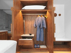 A wooden wardrobe with a built-in shelf, a hanging robe, and a small table with shoes and a scale. - The Oceanic Sportel (Ko Kaeo)