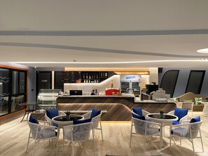 A modern bar area with a counter, seating, and a refrigerator labeled "Deluxe." - The Oceanic Sportel (Ko Kaeo)