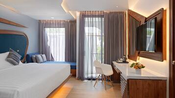 Una habitación de hotel con cama, escritorio, silla, televisor y cortinas.