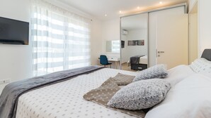 A bedroom with a bed, a desk, and a wardrobe.
