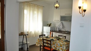 A dining area with a table set for four, chairs, a chandelier, and a kitchen in the background. - Nice 2-bedroom Private House, 50 m Beach, Sutivan (Sutivan)