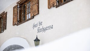 Um edifício com persianas de madeira e uma placa com a inscrição "Hus für Kirchgass".