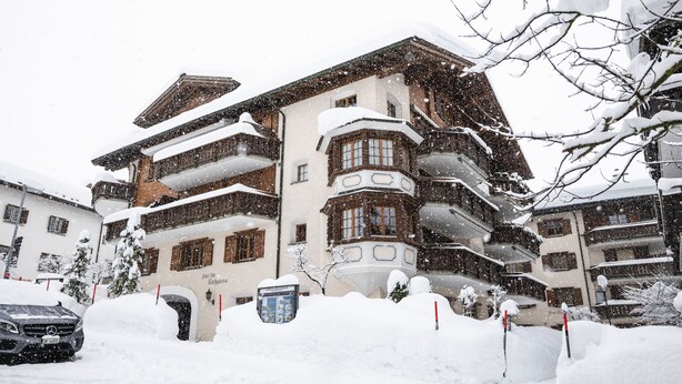 Um hotel com várias andares, varandas e paisagem coberta de neve.