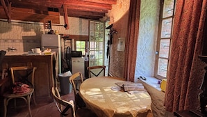 Une cuisine rustique avec des poutres en bois, un réfrigérateur et une fenêtre avec des rideaux.