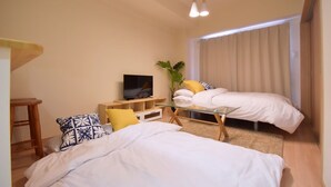A modern hotel room with two beds, a TV, a small table, and a window with curtains. - Chamomile Nishimachi 202 (Naha)