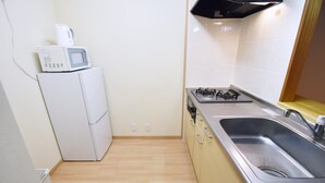 A compact kitchen with a microwave, stove, and sink. - Chamomile Nishimachi 202 (Naha)