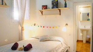 A bedroom with a bed, pillows, a shelf with books, a mirror, and a bathroom visible through an open door. - Mahalo Helthy House (Las Palmas de Gran Canaria)