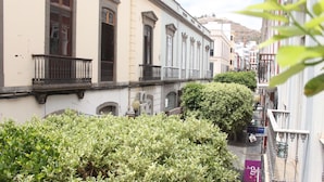 A narrow street with buildings on either side, featuring balconies and a small tree in the foreground. - Mahalo Helthy House (Las Palmas de Gran Canaria)