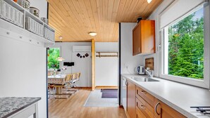 A modern kitchen with wooden cabinets, a large window, and a dining area with a table and chairs. - Stunning home in Hadsund with WiFi (Hadsund)