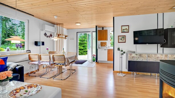 A spacious living area with a wooden ceiling, a dining table with chairs, a kitchen with a TV, and a fireplace. - Stunning home in Hadsund with WiFi (Hadsund)