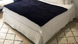 Ein Schlafzimmer mit einem Bett, einem Nachttisch und einem Fenster mit Vorhängen.