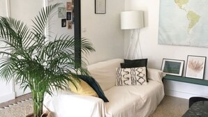 Ein Wohnzimmer mit einer Couch, einem Couchtisch, einer Lampe, einer Karte an der Wand und einer Topfpflanze.
