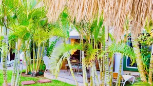 Un jardin luxuriant agrémenté de palmiers, un espace patio et un petit coin salon.