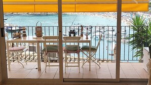 Una stanza con vista sul porto turistico, un tavolo con sedie e una finestra con persiane gialle.