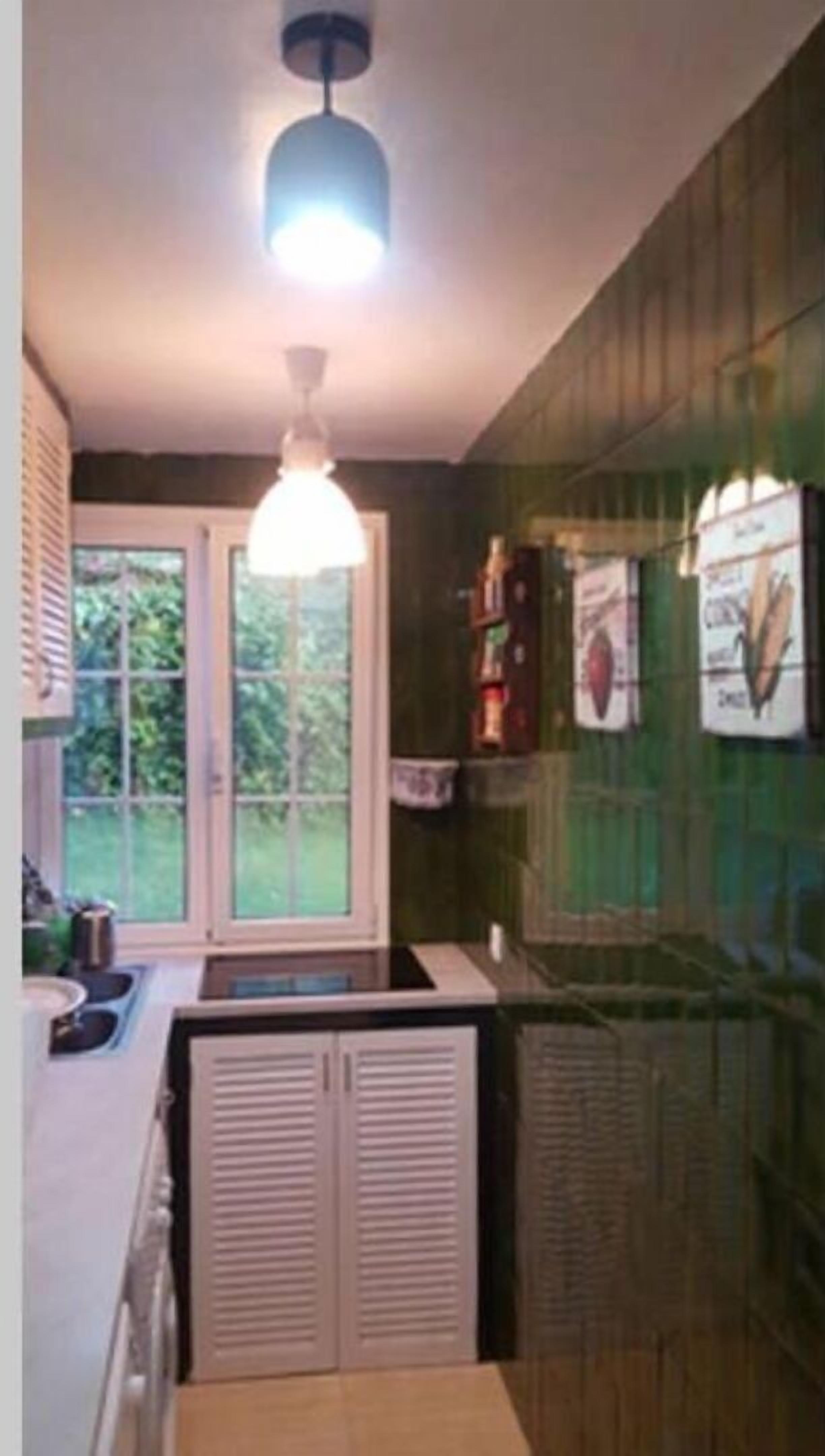 Una cocina compacta con ventana, una lámpara colgante y un horno empotrado.