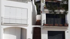 Un edificio su due piani con facciata bianca, un portone garage e un piccolo ingresso con porta in legno.