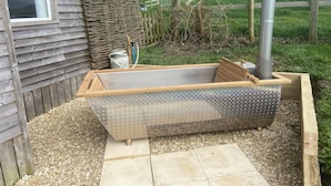 A hot tub with a wooden frame and metal base, surrounded by gravel and a wooden deck. - Cosy Rural Lodge at Goldhill Glamping - Sleeps 4 (Shaftesbury)