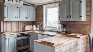 A kitchen with wooden cabinets, a built-in oven, a coffee maker, and a window. - Cozy home in Sjusjøen (Sjusjøen)