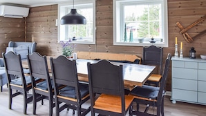 A dining area with a wooden table, black chairs, and a bench. There are two windows with white frames, a ceiling fan, and a wall-mounted shelf with decorative items. - Cozy home in Sjusjøen (Sjusjøen)