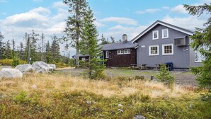 A two-story house with a dark exterior, numbered 1082, surrounded by a natural landscape with trees and rocks. - Cozy home in Sjusjøen (Sjusjøen)