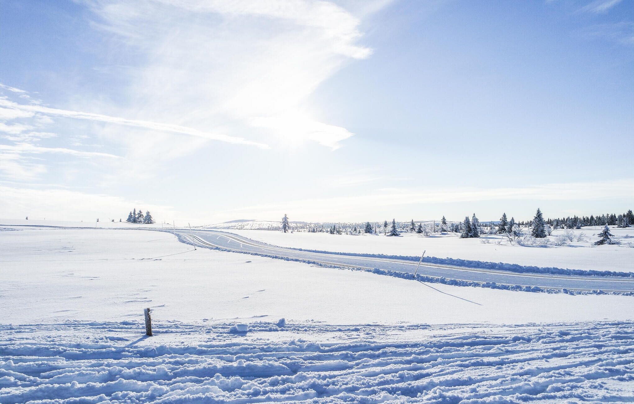 Eine verschneite Landschaft mit klarem Himmel und einer kurvenreichen Straße.